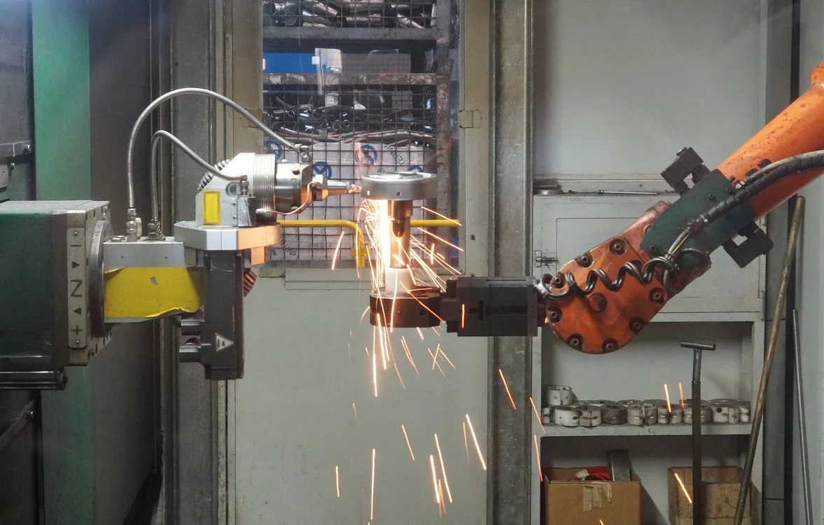 Industrial robotic arm welding with bright sparks: the coachsulting model applies one method to a real client's situation, not a generic script