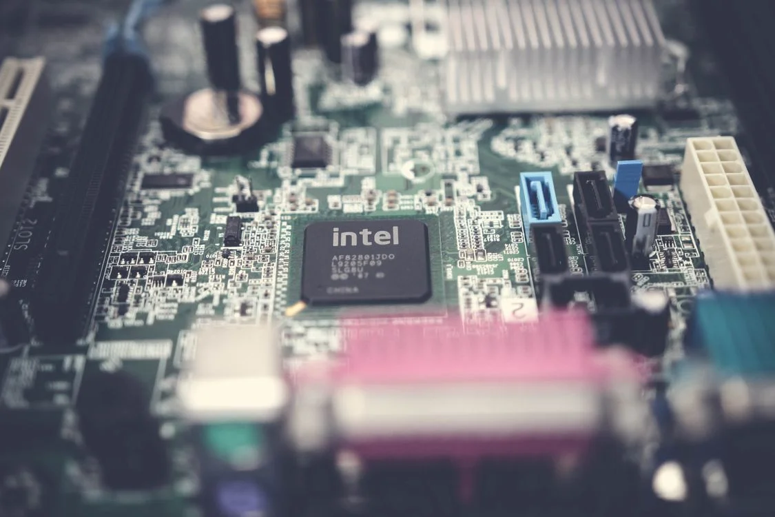 A colorful computer motherboard with a central processor chip, representing the shared single memory behind a custom GPT compared with an AI tool that knows your clients