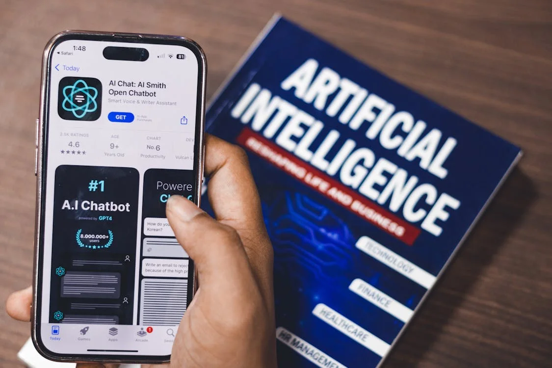 Smartphone displaying an AI app alongside a book on artificial intelligence — the tools redefining how consulting gets delivered