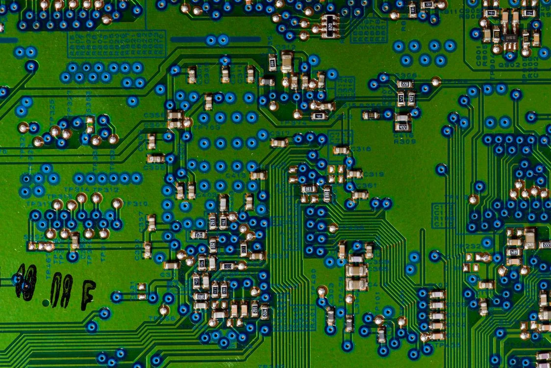 A green circuit board with rows of blue-ringed solder points, representing the structural separation an AI tool needs to keep client data separate
