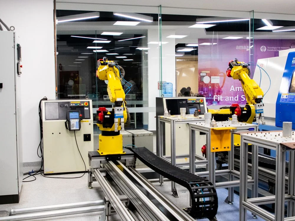 Industrial robotic arms running side by side in a modern automation lab, representing one methodology delivered to 100 clients without you producing the work