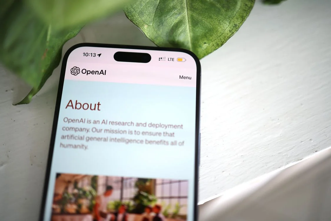 A smartphone showing an AI website resting among green leaves, representing the free tools every business model now competes with
