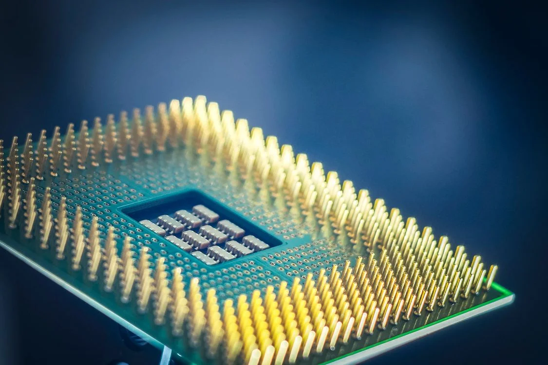 Macro shot of a gold-pinned CPU chip on a blue background, representing the question of whether ChatGPT is safe for client work at the architecture level