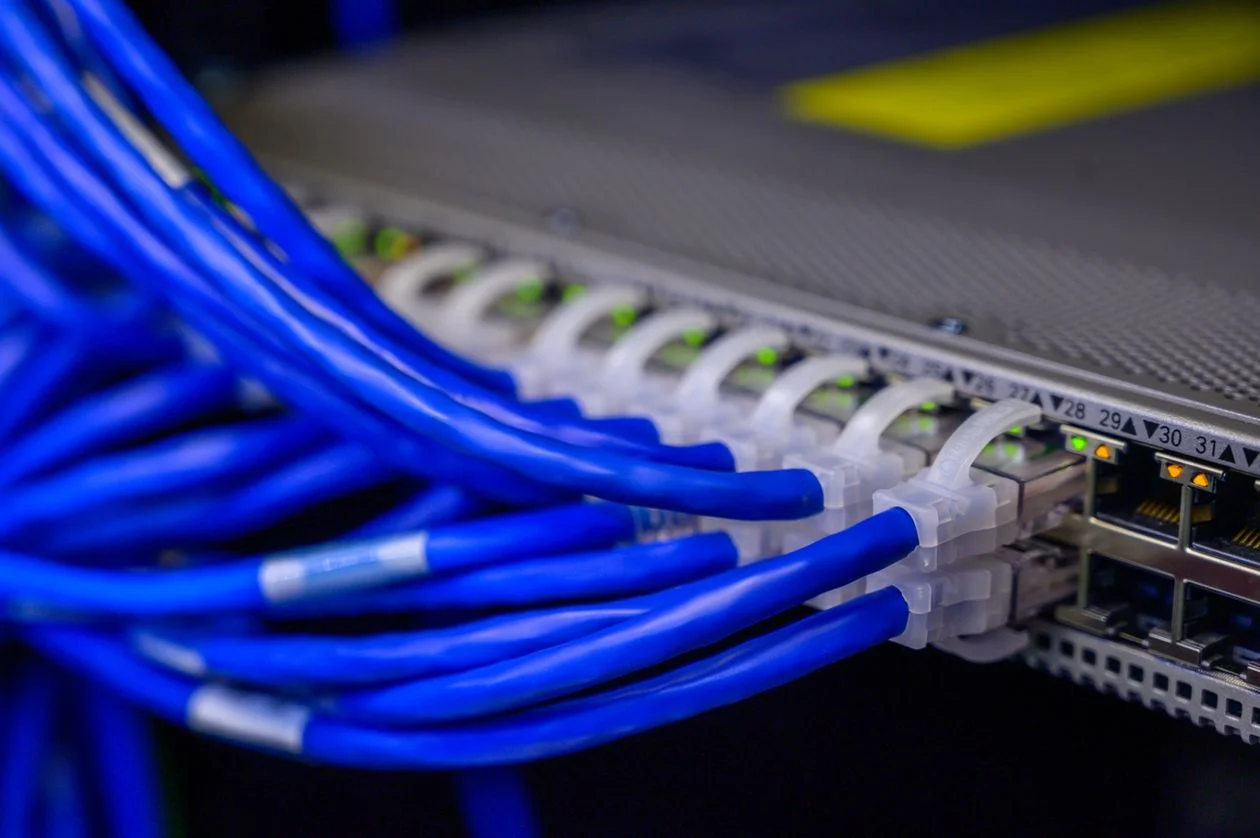 Blue ethernet cables connected to a network switch in a data center, representing an AI knowledge base for consultants that keeps every client in its own isolated workspace