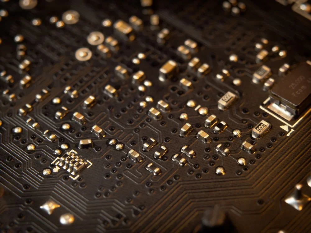 Macro view of a gold circuit board, representing the system layer that carries the information half of high-ticket coaching