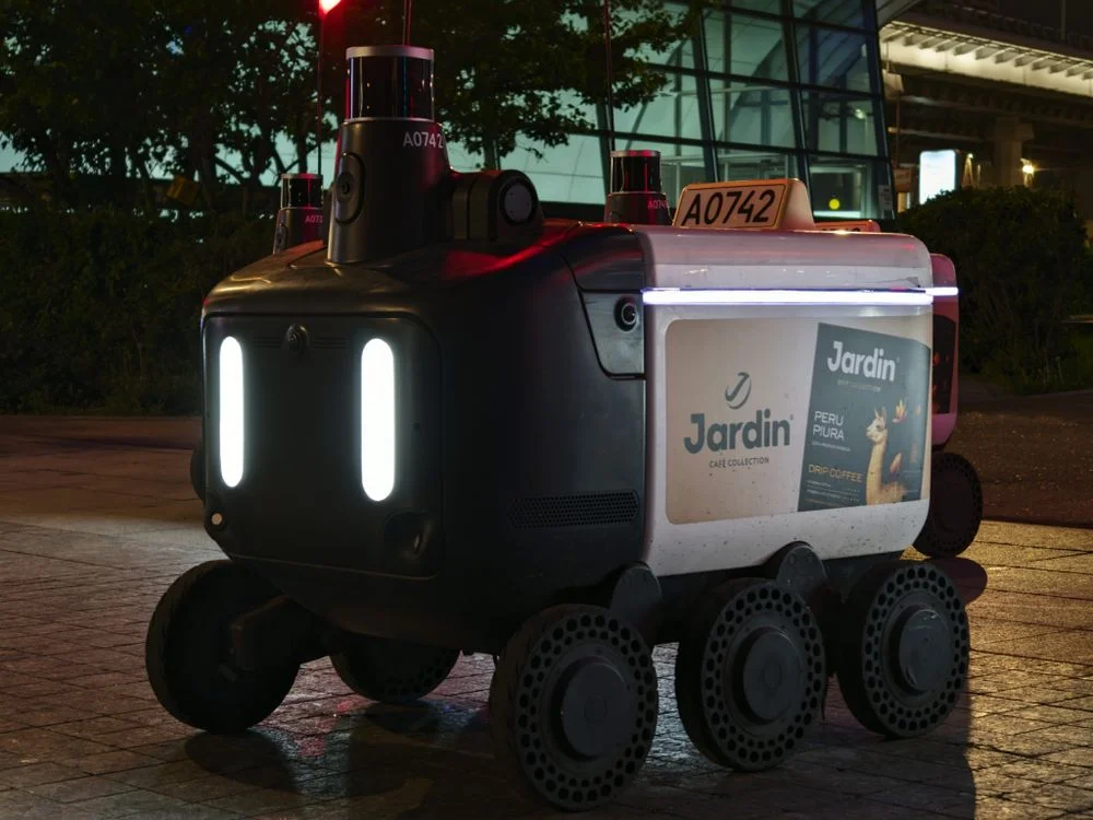 An autonomous delivery robot on a city street at night, illustrating where the line sits between AI to handle routine client questions and work that needs judgment