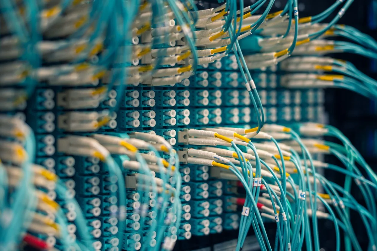 Blue network cables organized in a patch panel in a server room, representing client context held in separate, isolated workspaces inside an AI knowledge base for consultants