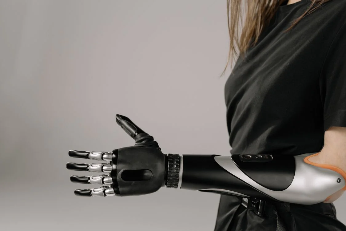 Robotic prosthetic arm extended in a handshake gesture, representing the machine half of the future of high-ticket coaching