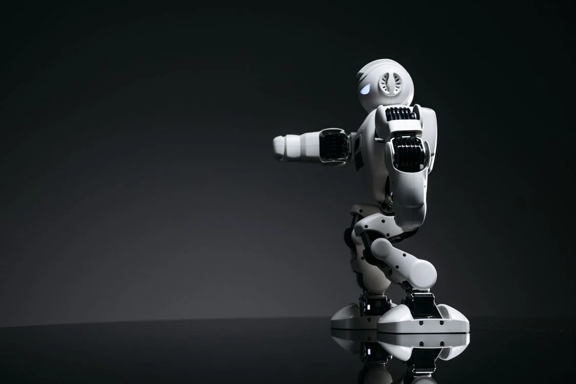 White robot on a dark reflective surface, representing a proprietary AI system for consultants built on their own frameworks