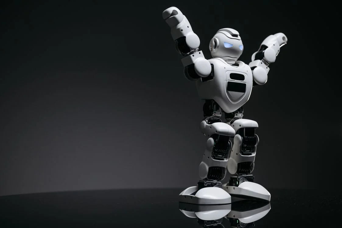 White humanoid robot with arms raised, representing the AI client onboarding process running the repeatable work so the consultant keeps the relationship