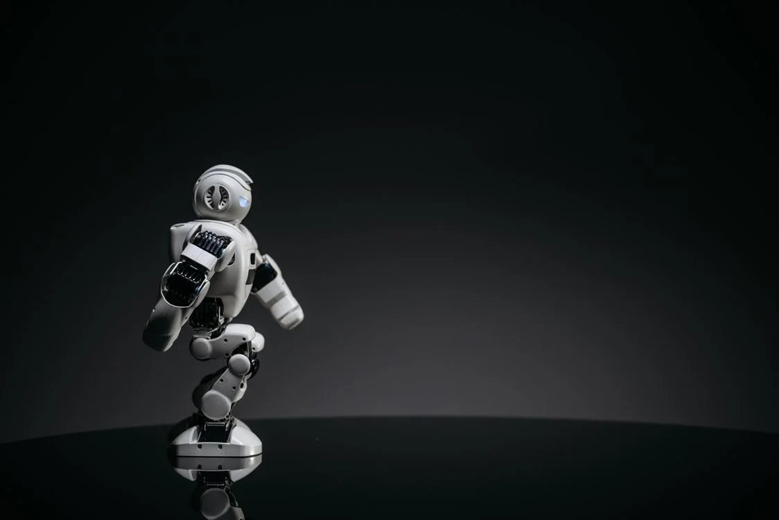 Sleek white robot poised against a dark studio backdrop, representing an AI workspace that applies your methodology to one client at a time