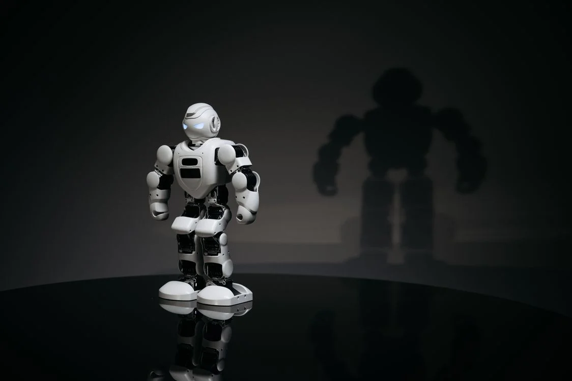 White humanoid robot casting a large shadow, representing a system that carries a consultant's methodology so they can take on more clients without losing quality