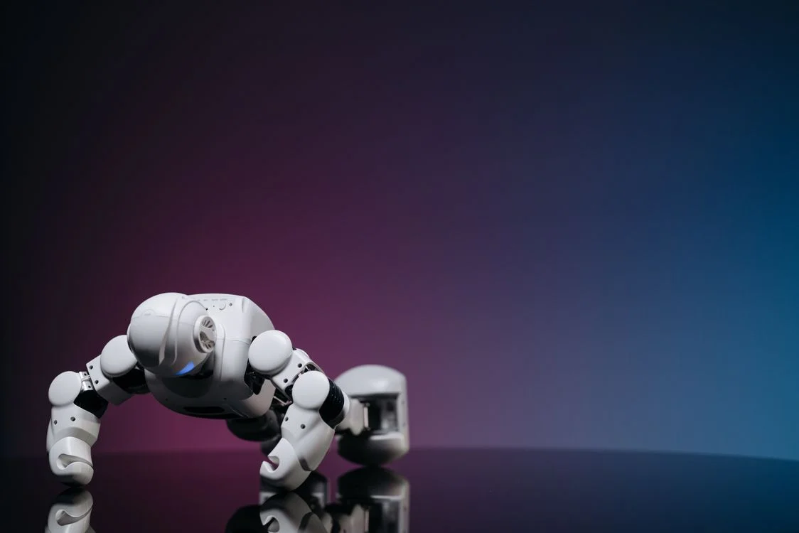 White humanoid robot on a reflective surface, representing AI coaching apps and the question of whether AI will replace coaches who only deliver generic advice