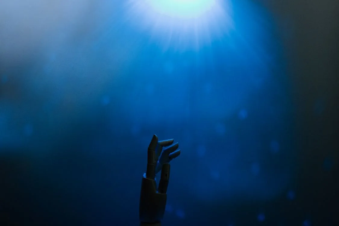 A robotic hand reaching toward a glowing blue light, representing AI for client work that keeps each client’s data isolated by design