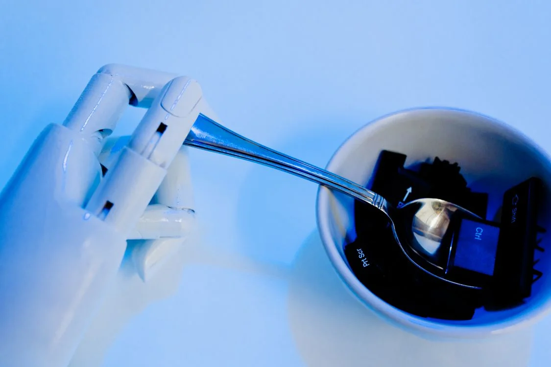 Robotic hand arranging keyboard keys, representing how to scale your methodology with AI by turning a framework into something a system can apply