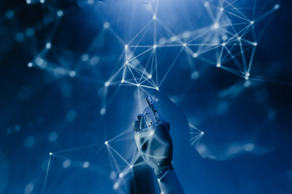 Digital robotic hand reaching toward a glowing blue network — the intersection of AI capability and consulting methodology