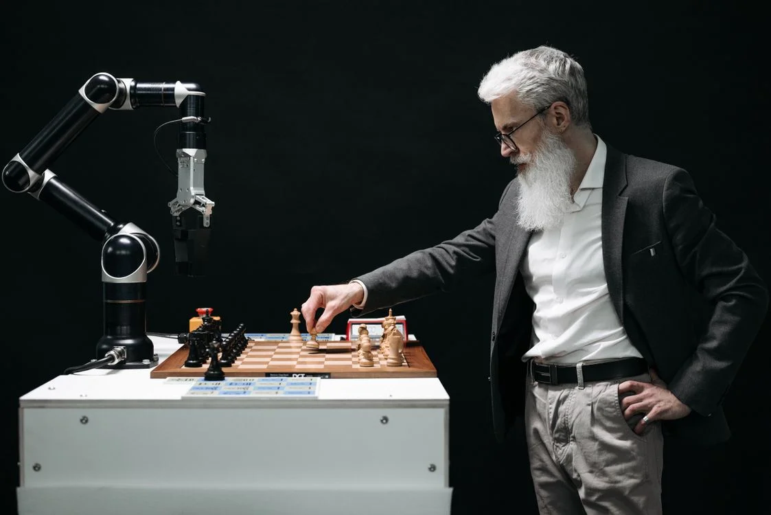 A man playing chess against a robotic arm, representing the split between routine client questions AI can handle and the judgment that stays with you
