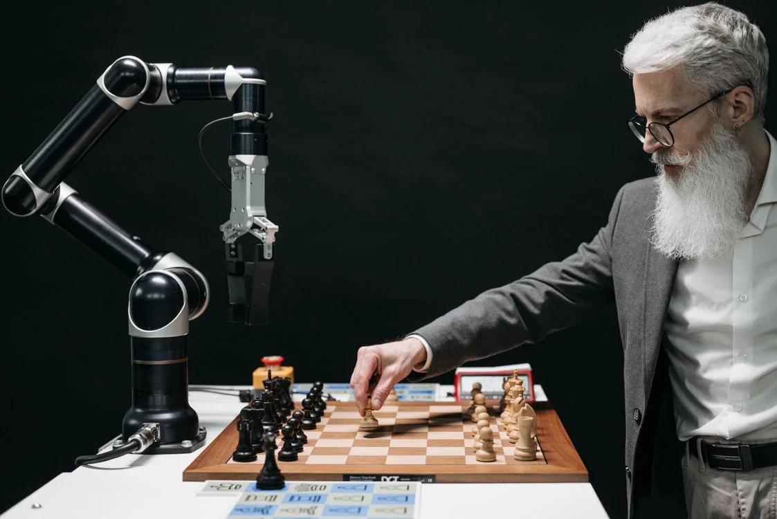 A man in a suit moving chess pieces against a robotic arm, representing the human judgment that decides when AI is safe for confidential client work