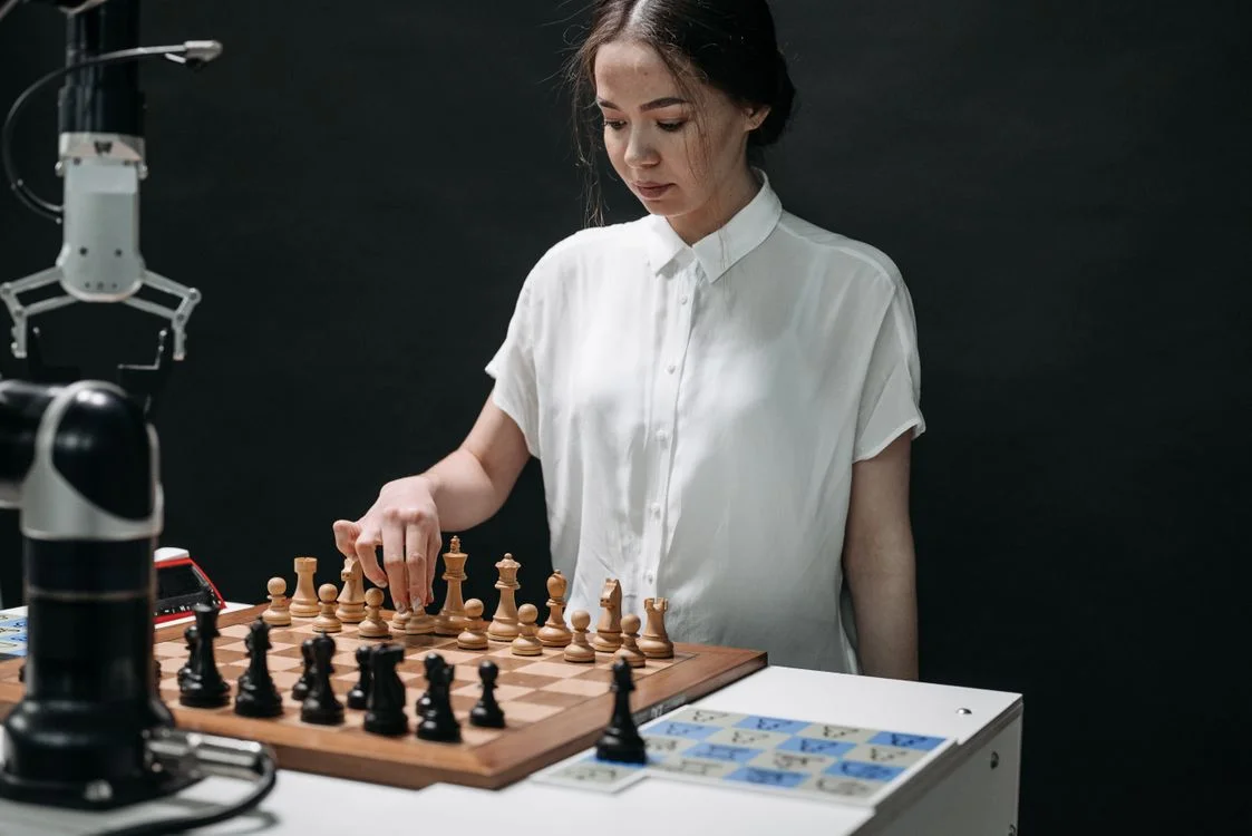 A person playing chess against a robotic arm, representing the choice between human-run discipline and a system that isolates each client by design