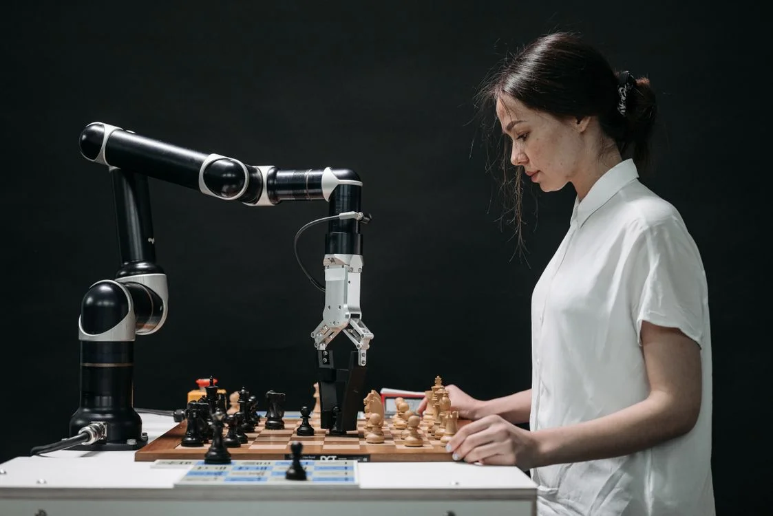 Woman playing chess against a robot, showing a service provider directing AI trained on proprietary knowledge rather than being replaced by it