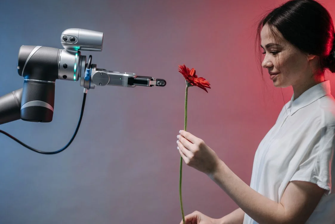 Robotic arm handing a flower to a person, representing the handoff between human judgment and the routine work AI handles when you automate client onboarding