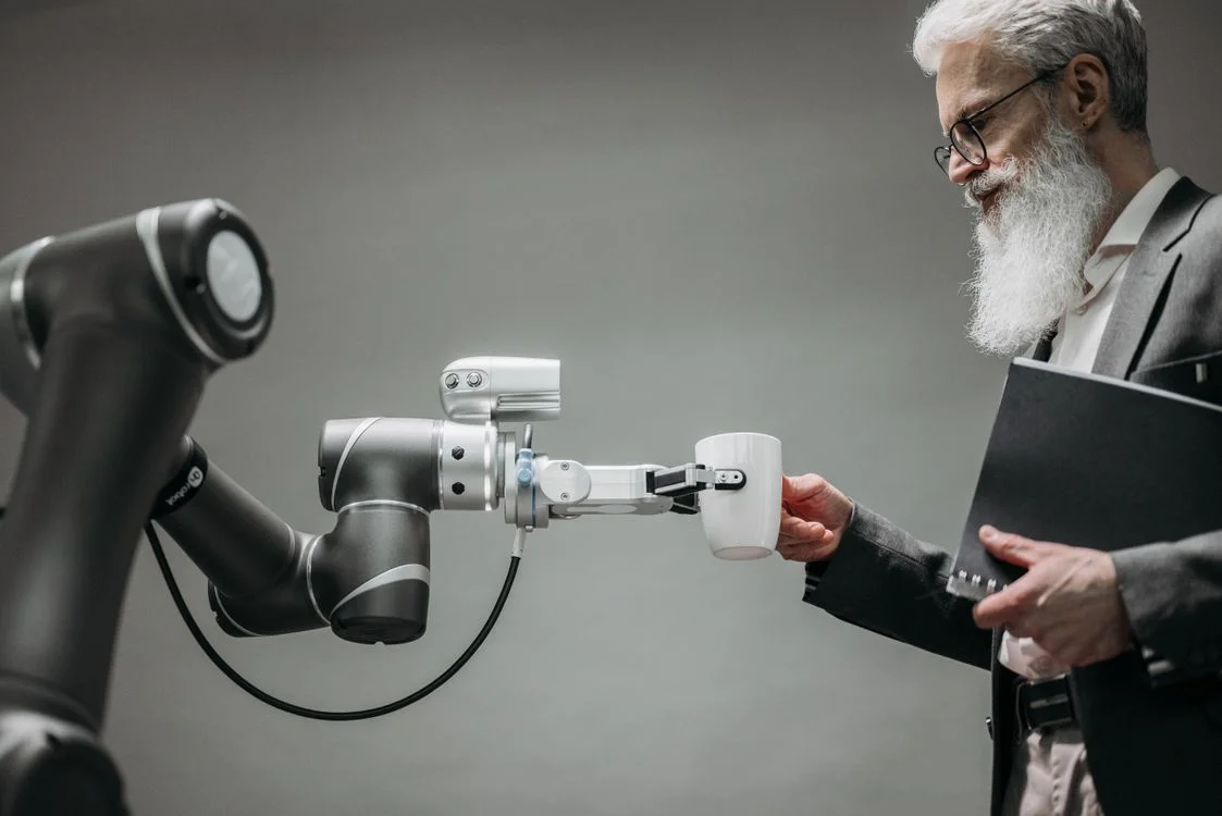 Robotic arm handing over a cup, representing AI for marketing agencies handing finished, on-brand work back to the operator for review