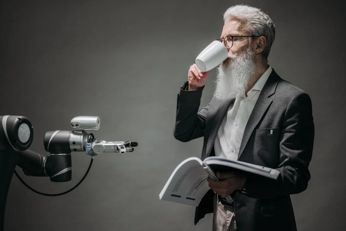 An older man interacting with a robot while holding a book, representing the shift from selling information to delivering applied expertise