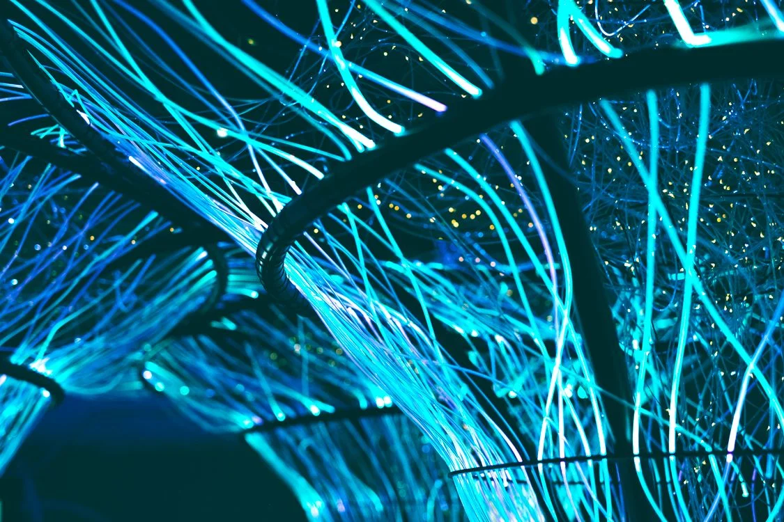 Glowing neon-blue optical fibers forming a dense grid, representing isolated client workspaces running one methodology in AI service delivery