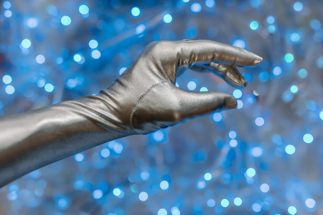 Silver robotic hand reaching against blue light, representing what happens when you clone your expert methodology into an AI system