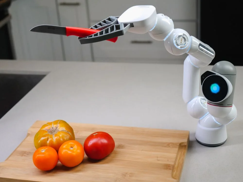 A robotic arm slicing tomatoes in a kitchen, representing the setup steps for using AI to handle routine client questions consistently