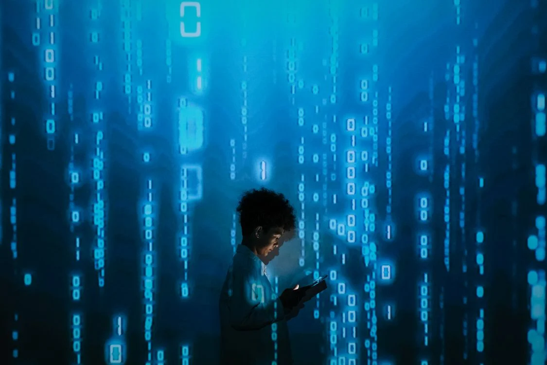 A figure surrounded by falling blue binary code, representing client data with no boundaries around it before separate AI workspaces per client are set up